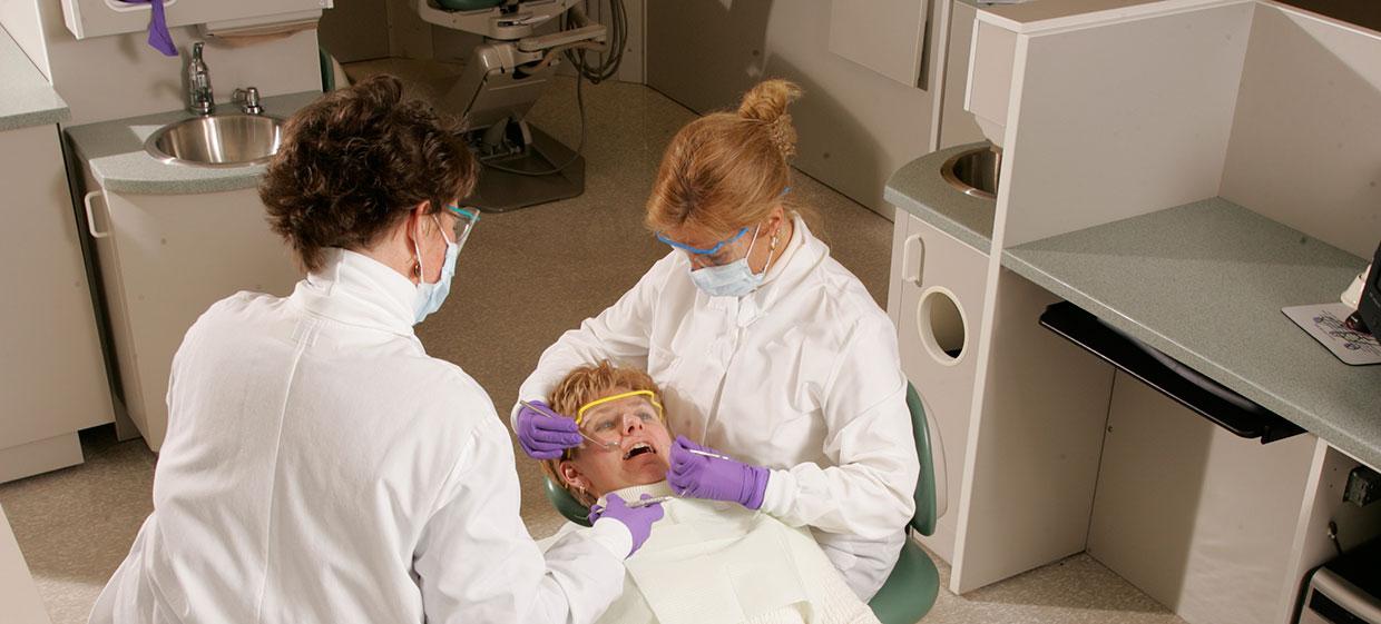 Dental assisting students working with dentist on patient